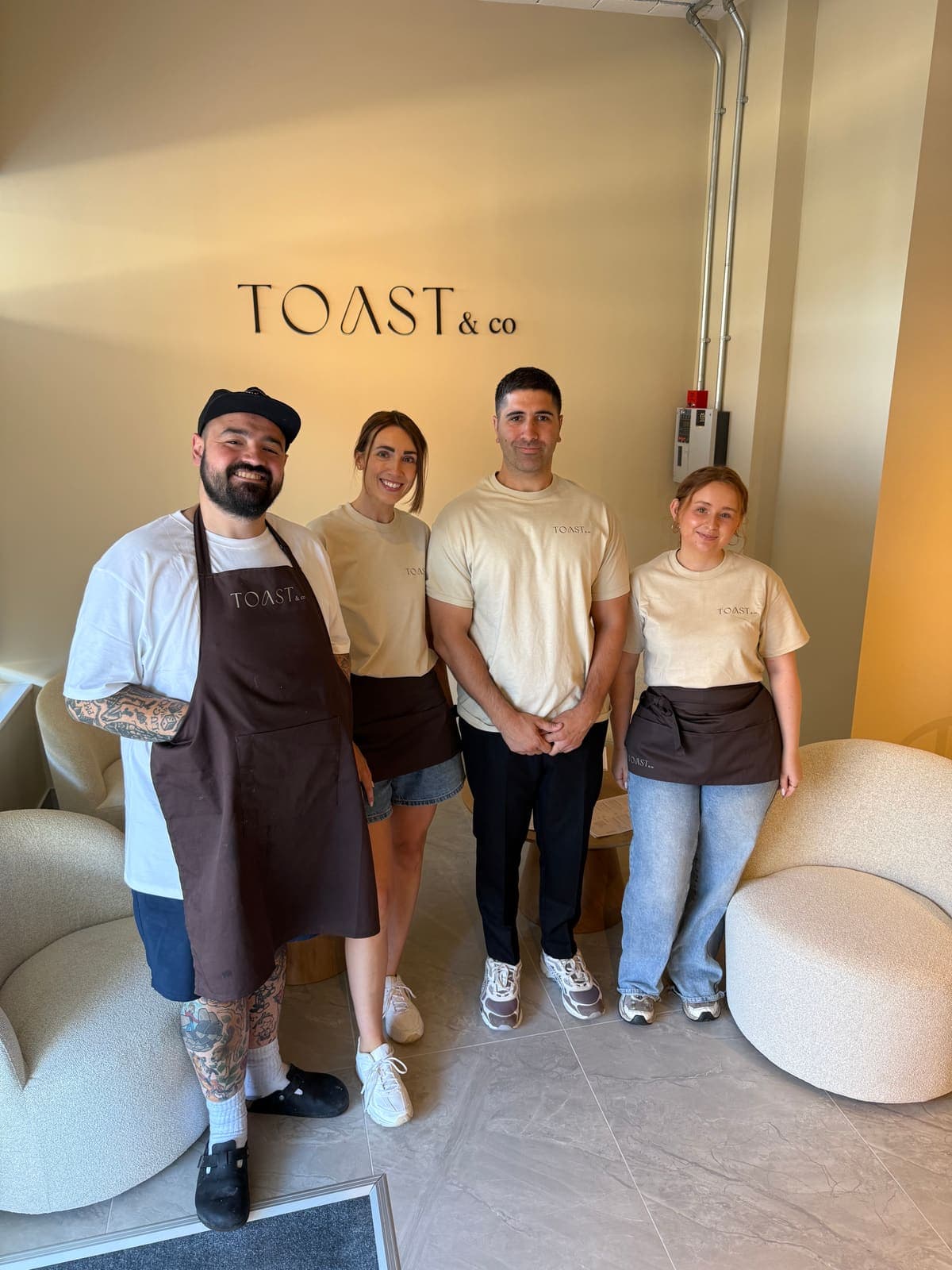 The TOAST & Co team standing beneath the café sign inside their Allestree, Derby café